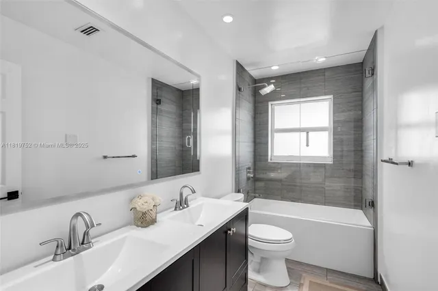 a bathroom with a toilet a sink a tub and mirror