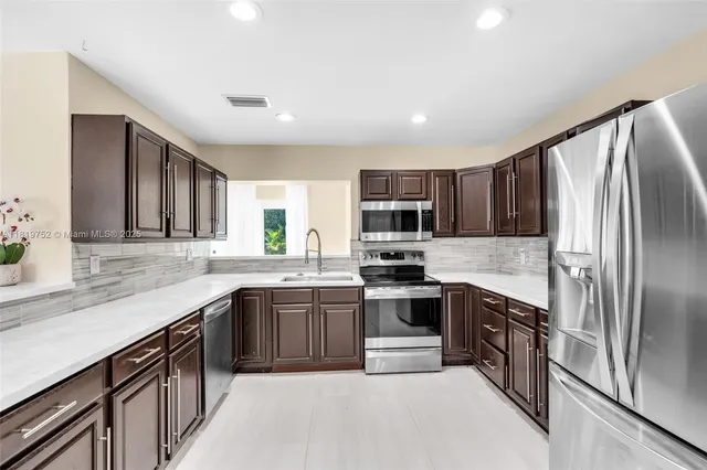 a kitchen with stainless steel appliances granite countertop a sink stove microwave and refrigerator
