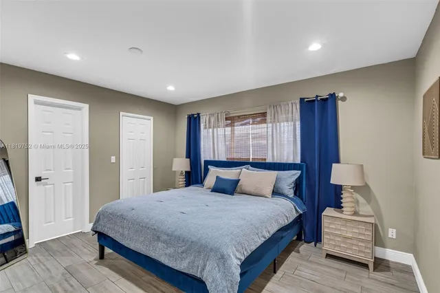 a bedroom with a large bed and wooden floor