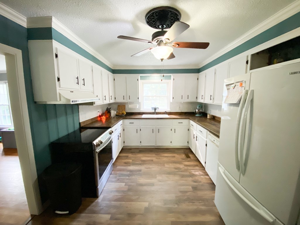 173 Magnolia Street Camden, TN 38320 - Photo 4 of 22 a kitchen with stainless steel appliances a refrigerator a sink a stove a microwave oven with white cabinets