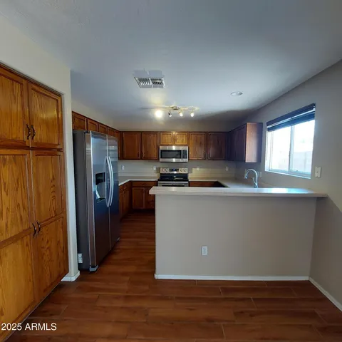 a kitchen with stainless steel appliances granite countertop a refrigerator a sink dishwasher a stove and white countertops with wooden floor