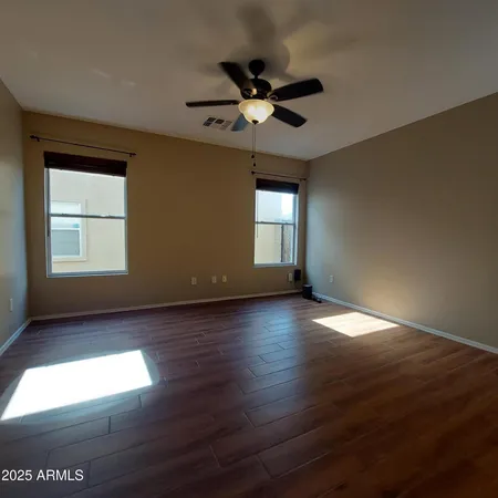 a view of empty room with wooden floor and fan