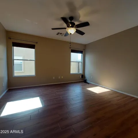 a view of empty room with wooden floor and fan