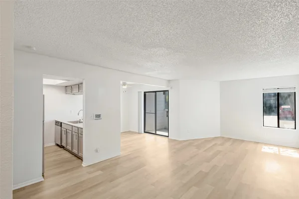a view of an empty room with wooden floor and windows