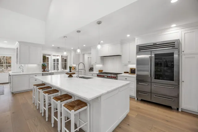 a large white kitchen with kitchen island a stove a table and chairs