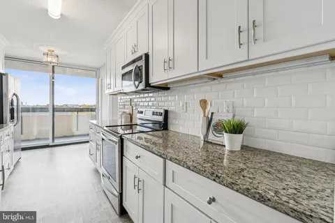 a kitchen with stainless steel appliances granite countertop a sink a stove and cabinets