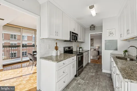 a kitchen with stainless steel appliances granite countertop a stove top oven a sink a microwave and a refrigerator