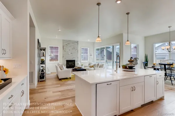a kitchen with sink stove and white cabinets with wooden floor