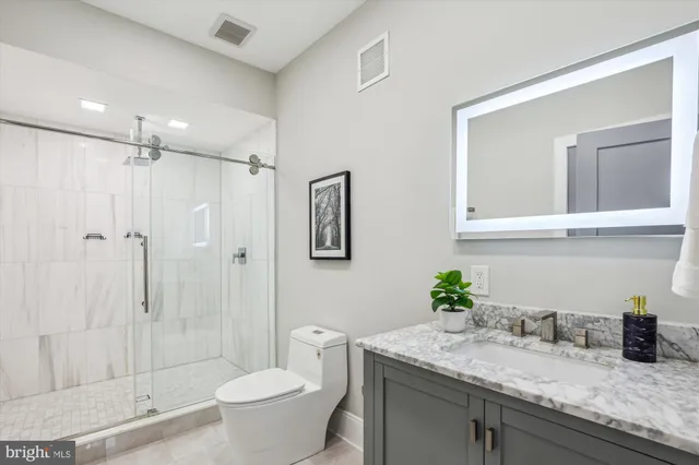 a bathroom with a granite countertop sink a toilet and shower