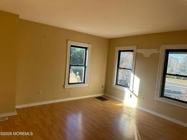a view of an empty room with window and wooden floor