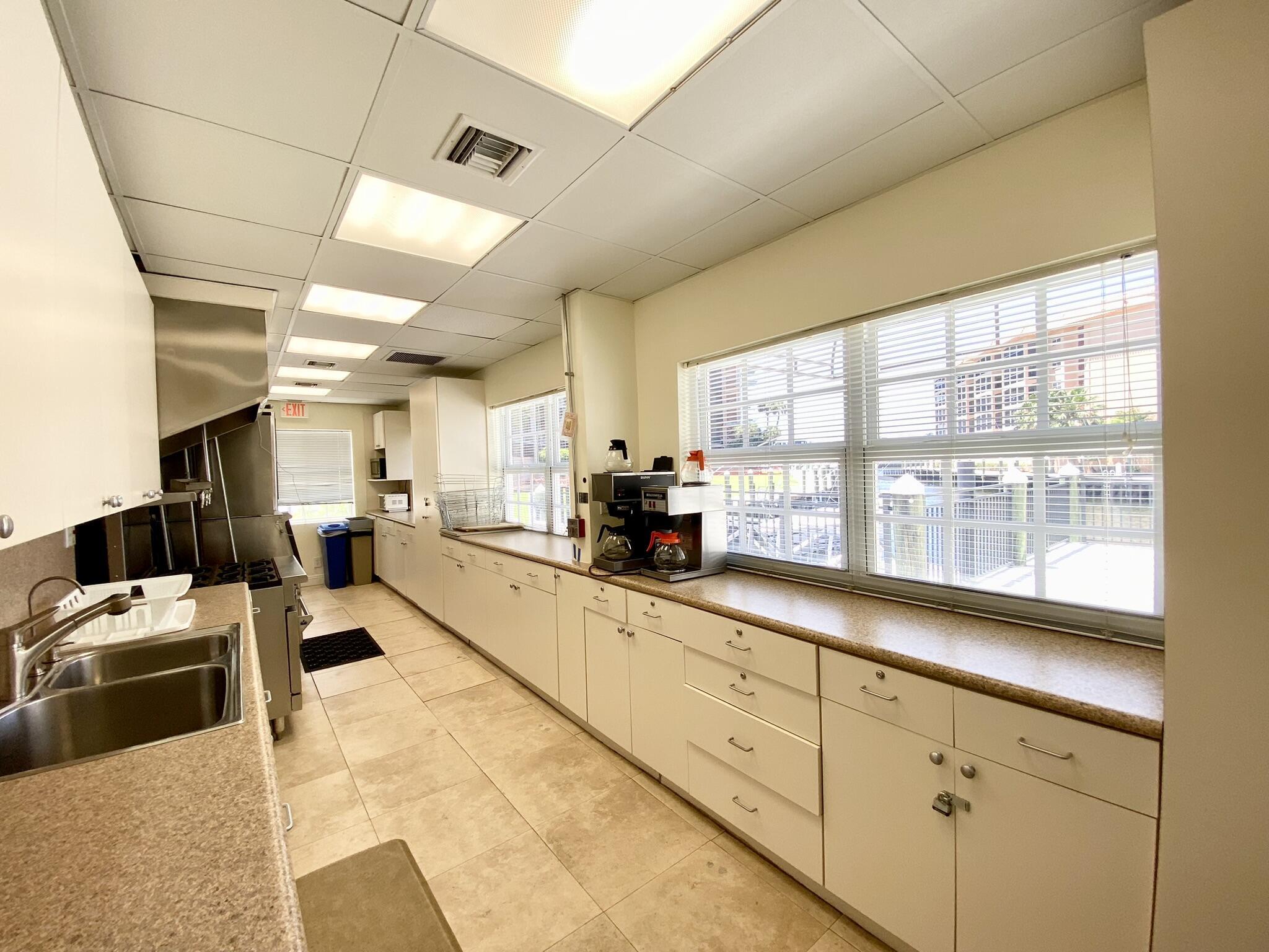 2871 North Ocean Boulevard, Unit M330 Boca Raton, FL 33431 - Photo 45 of 60 a large white kitchen with lots of counter top space and stainless steel appliances