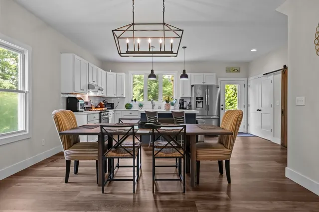 a kitchen with stainless steel appliances granite countertop a dining table chairs refrigerator a sink and dishwasher