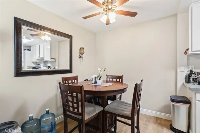 a kitchen with stainless steel appliances granite countertop a sink a stove a refrigerator a dining table and chairs with wooden floor