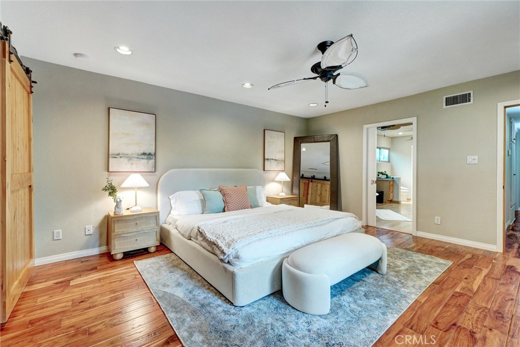 14955 Haynes Street Van Nuys, CA 91411 - Photo 18 of 35 a spacious bedroom with a large bed chandelier and a dresser