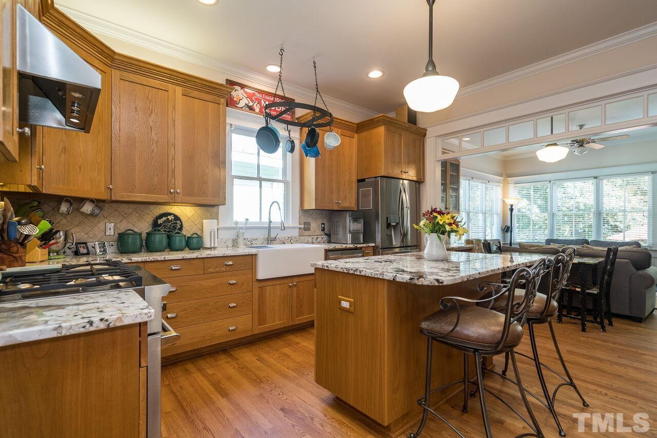 1218 Filmore Street Raleigh, NC 27605 - Photo 12 of 38 a kitchen with stainless steel appliances granite countertop a stove a sink a refrigerator a dining table and chairs with wooden floor