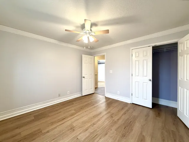 an empty room with wooden floor fan and windows