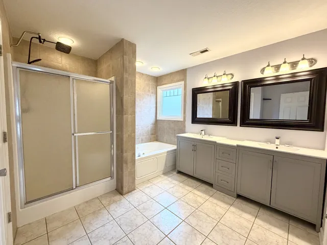 a bathroom with a double vanity sink mirror and bathtub
