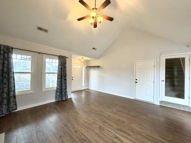 a view of an empty room with a window and wooden floor