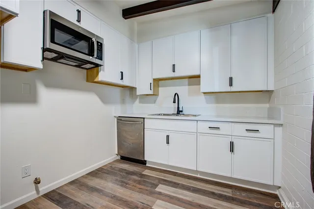 a kitchen with granite countertop a sink cabinets and stainless steel appliances