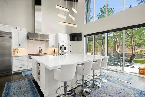 a large white kitchen with stainless steel appliances a stove a refrigerator a fireplace with white cabinets and wooden floor