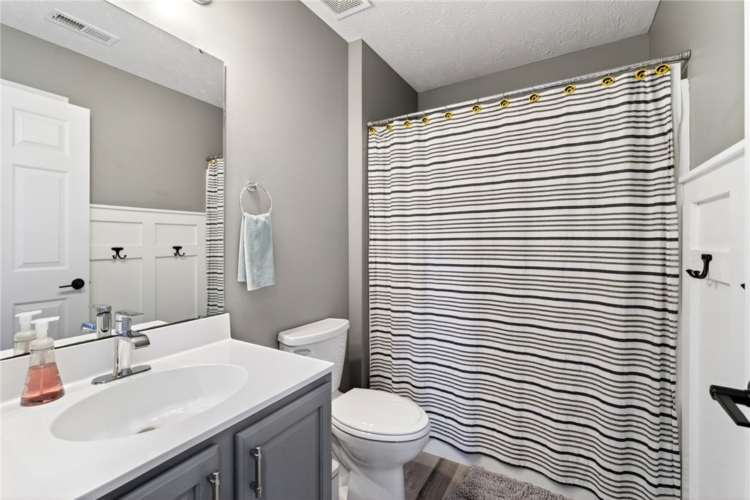 39 Holly Court Springboro, OH 45066 - Photo 22 of 42 This clean and functional bathroom features a single vanity, toilet, and shower with a striped curtain.