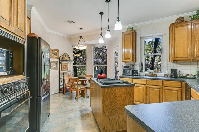 a view of a kitchen with kitchen island granite countertop a sink a counter and windows
