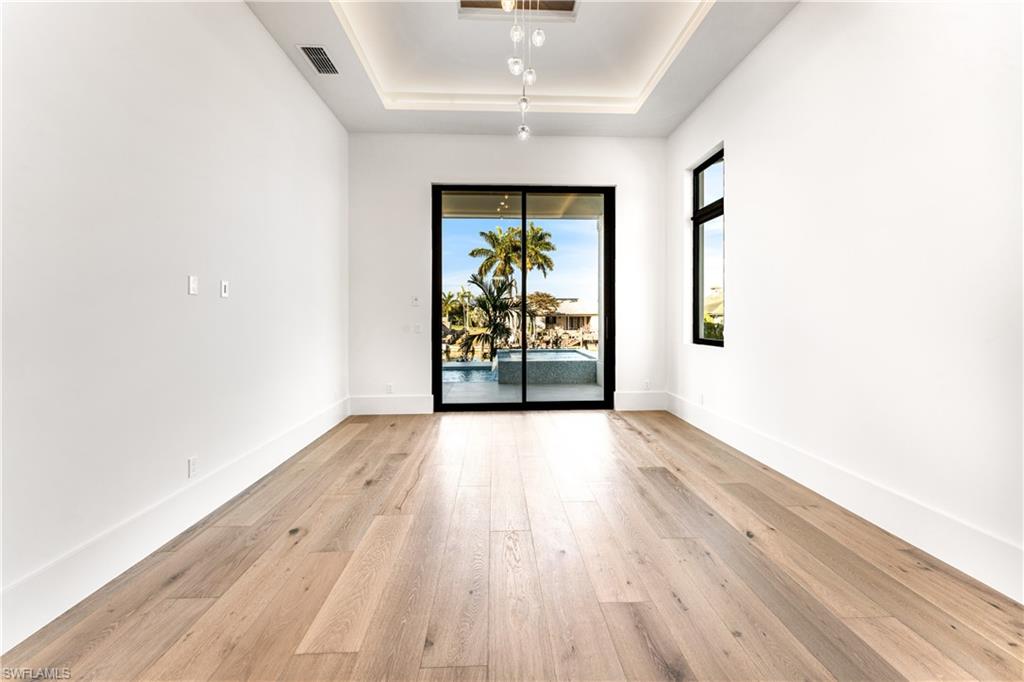 159 Dan River Court Marco Island, FL 34145 - Photo 25 of 38 Empty room with a tray ceiling and light wood-type flooring