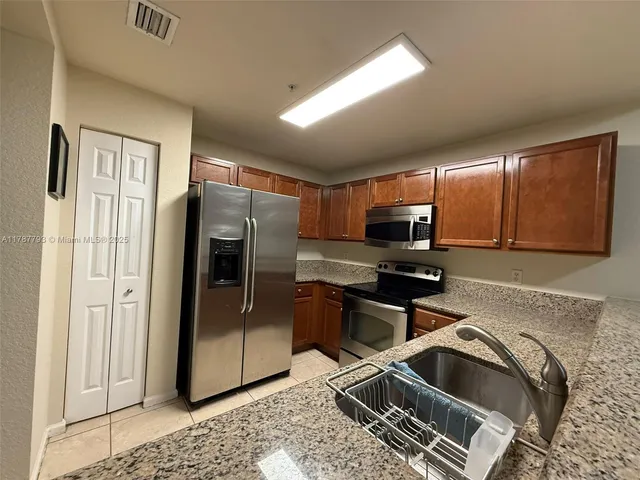 a kitchen with stainless steel appliances granite countertop a refrigerator and a sink