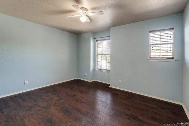 a view of empty room with wooden floor and fan