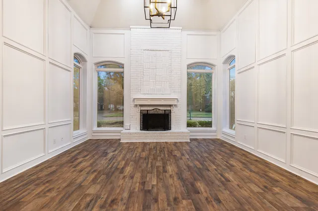 a view of a livingroom with wooden floor a fireplace and windows