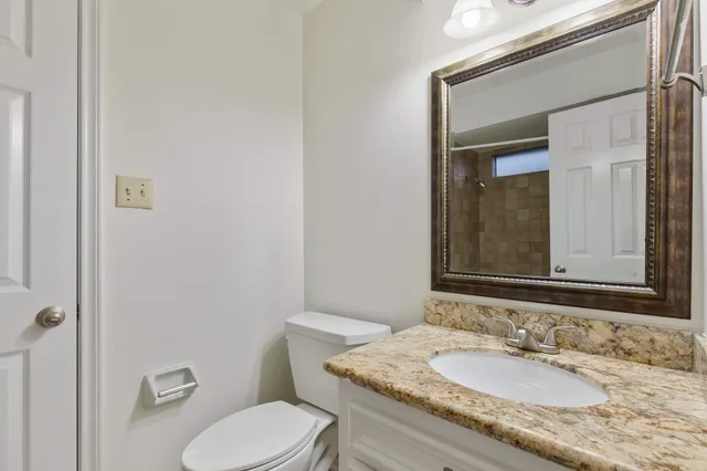a bathroom with a granite countertop toilet sink and mirror