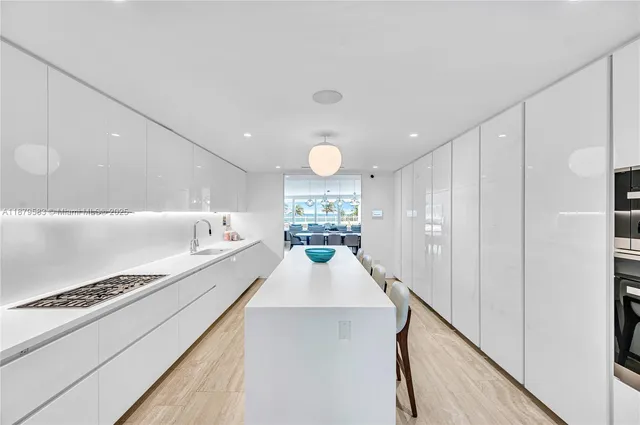 a large white kitchen with kitchen island a stove a sink and a refrigerator with wooden floor