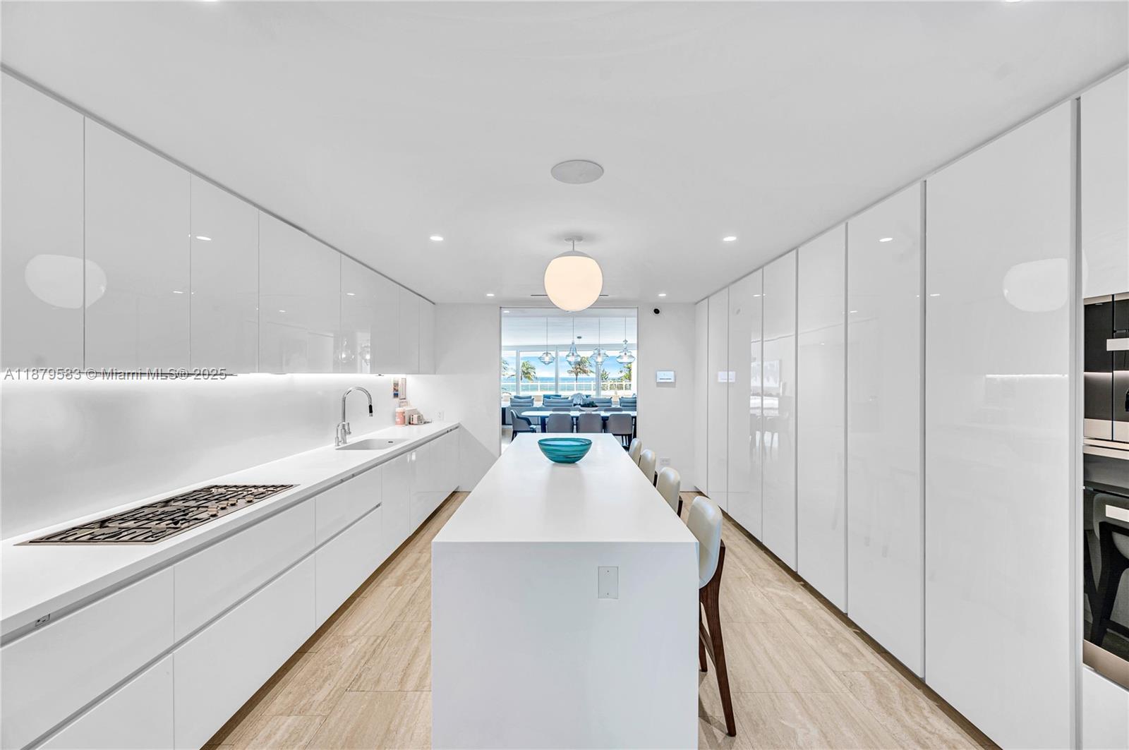 9001 Collins Avenue, Unit S201 Surfside, FL 33154 - Photo 18 of 44 a large white kitchen with kitchen island a stove a sink and a refrigerator with wooden floor