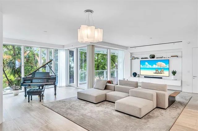 a living room with furniture a floor to ceiling window and wooden floor