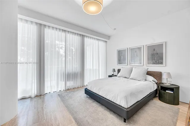 a bedroom with a bed lamp and a large window