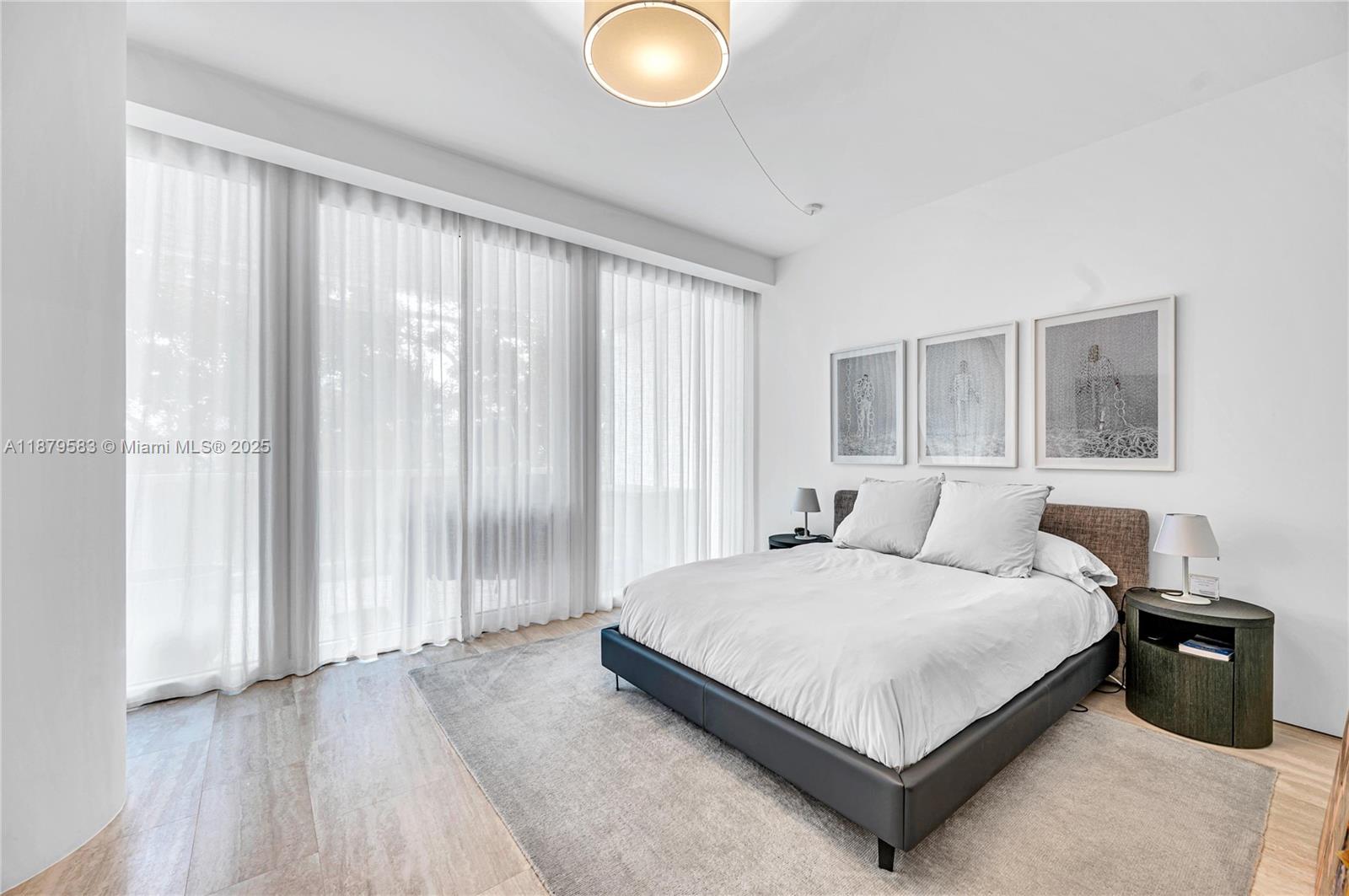 9001 Collins Avenue, Unit S201 Surfside, FL 33154 - Photo 41 of 44 a bedroom with a bed lamp and a large window