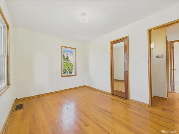 a view of an empty room with wooden floor and a window