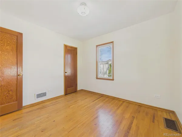 a view of an empty room with window and wooden floor