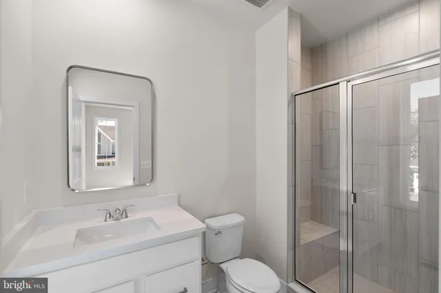 a bathroom with a toilet sink vanity and mirror