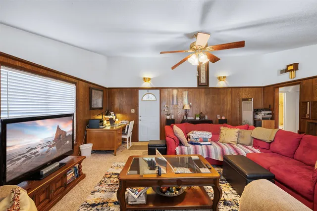 a living room with furniture a flat screen tv and floor to ceiling window