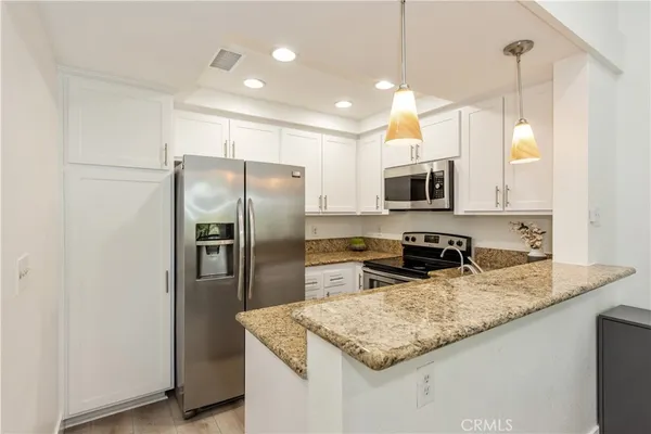 a kitchen with granite countertop a refrigerator a sink a stove a microwave and island