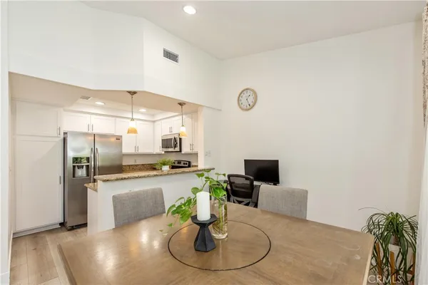 a kitchen with stainless steel appliances kitchen island granite countertop a refrigerator a stove and a sink with wooden floor