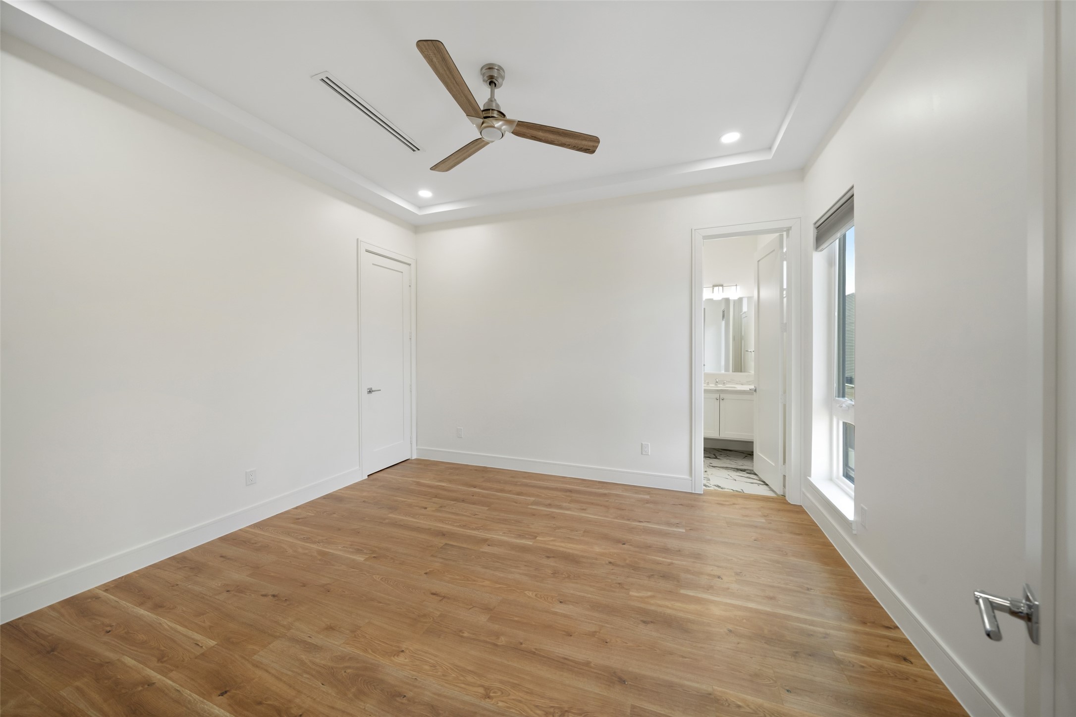 1839 Colquitt Street Houston, TX 77098 - Photo 9 of 19 Bedroom #2 features a modern design with hardwood floors, a ceiling fan, and recessed lighting. It includes a doorway leading to a bathroom and a large window for natural light.