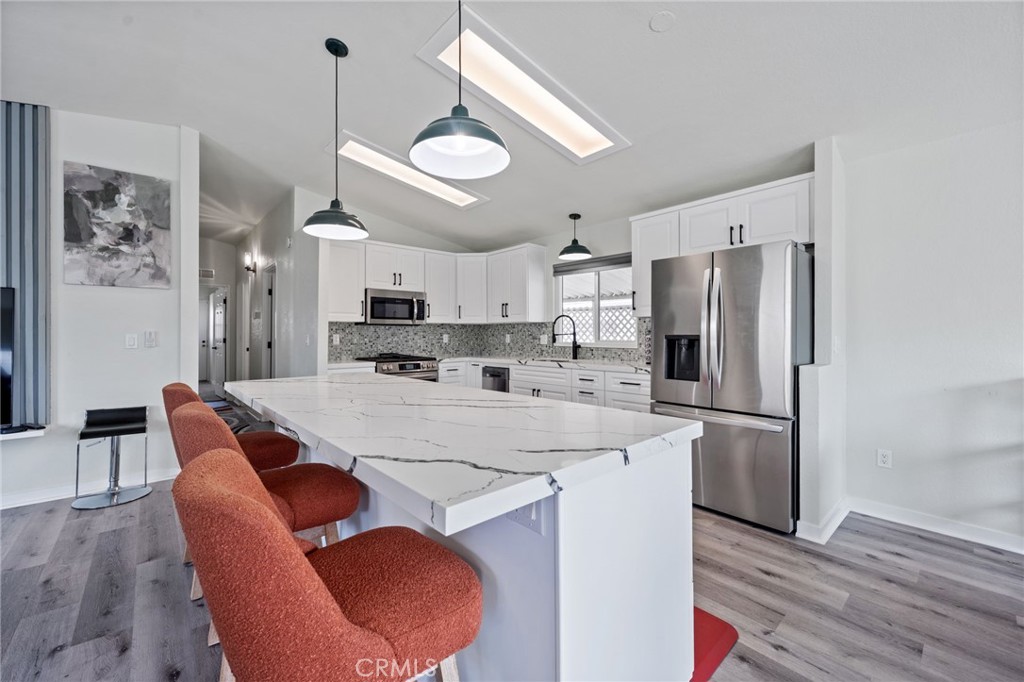 65 Hummingbird Lane Oceanside, CA 92057 - Photo 11 of 38 a kitchen with stainless steel appliances granite countertop a dining table chairs refrigerator and cabinets