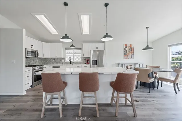 a kitchen with stainless steel appliances granite countertop a dining table chairs stove and white cabinets