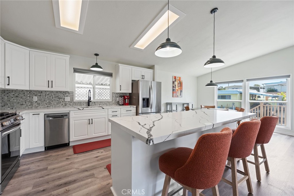65 Hummingbird Lane Oceanside, CA 92057 - Photo 13 of 38 a large kitchen with granite countertop a stove a sink a dining table and chairs with wooden floor
