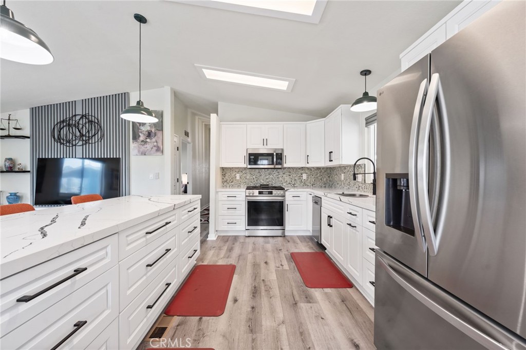 65 Hummingbird Lane Oceanside, CA 92057 - Photo 14 of 38 a kitchen with stainless steel appliances granite countertop a refrigerator a oven and white cabinets with wooden floor