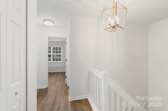 a view of a hallway with wooden floor and staircase