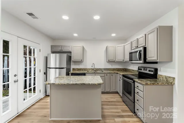 a kitchen with stainless steel appliances granite countertop a sink stove microwave and refrigerator