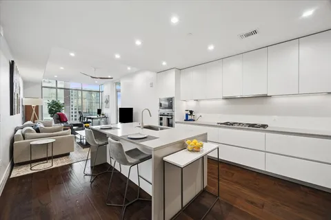 a kitchen with a stove a sink dishwasher a refrigerator and white cabinets with wooden floor